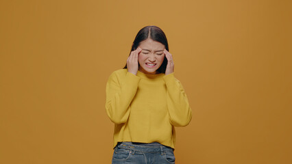 Young adult screaming because of headache on camera, rubbing temples to cure pain. Unwell person in...