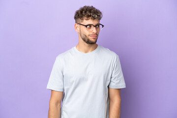 Fototapeta premium Delivery caucasian man isolated on purple background making doubts gesture looking side
