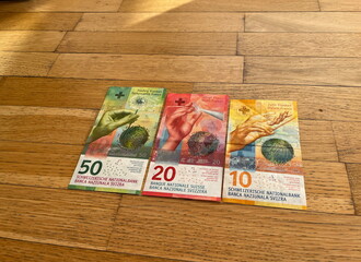 Fototapeta na wymiar Colorful Swiss francs on the wooden background. Currency. Switzerland. CHF. Swiss. Money