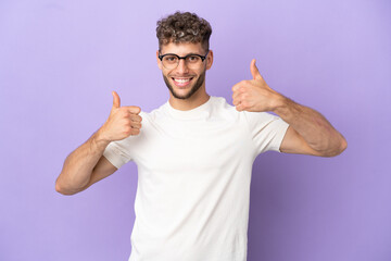 Fototapeta premium Delivery caucasian man isolated on purple background giving a thumbs up gesture