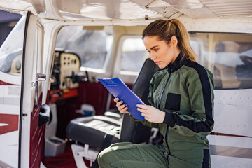 Concentrated caucasian woman, leaning onto the plane, reading so