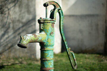 Old hand water pump on a well in the garden, watering and saving water, rural environnement