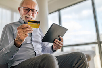 Blured portrait of elderly cheerful and happy male buying and paying online, transferring funds and...