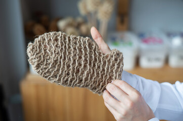 Woman holding eco body sponge in the shape of a mitten. Natural products with zero waste