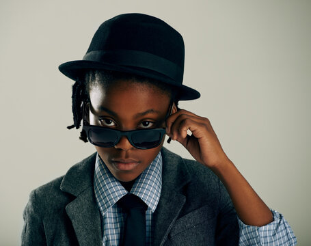 Dressed in his best. Studio shot of a cool ethnic boy peering over his sunglasses.