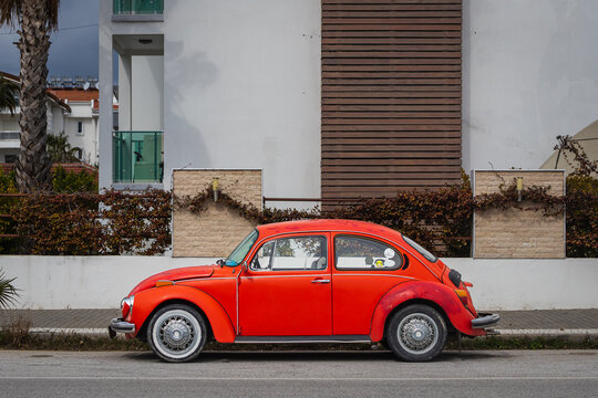 Side; Turkey – February 20 2022: Vintage red car Volkswagen Beetle on the background of a city street, side   view. Legendary retro car in an urban environment