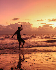 Fototapeta na wymiar silhueta de homem não identificado pulando ondas durante o nascer do sol na Ponta do Seixas, Paraíba