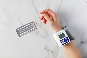 Measuring Blood pressure with modern hand tonometer, with piils blister, marble background
