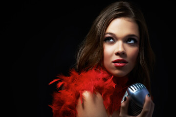 Naklejka premium Sultry songstress. Shot of an attractive young singer holding an old-fashioned microphone.