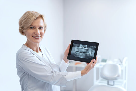 Dentist holding digital tablet with teeth x-rays