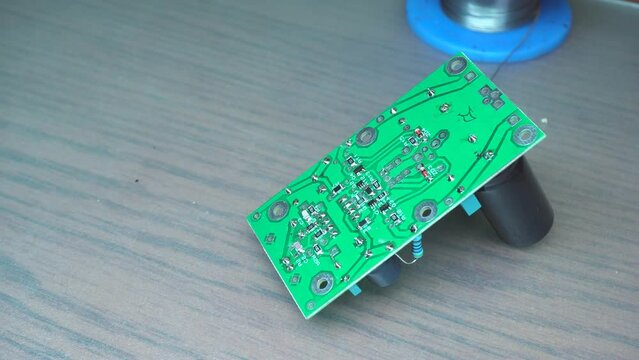 components mounted on a board, soldering station, solder, men's hands are soldered