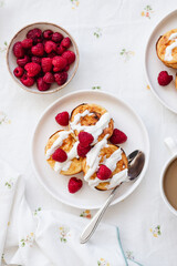 Cottage cheese pancakes in white plate. Syrniki with raspberries and sour cream. Homemade breakfast or lunch.