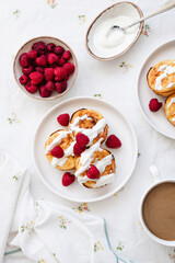 Cottage cheese pancakes in white plate. Syrniki with raspberries and sour cream. Homemade breakfast or lunch.