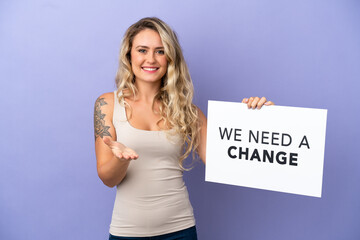 Young Brazilian woman isolated on purple background holding a placard with text We Need a Change making a deal