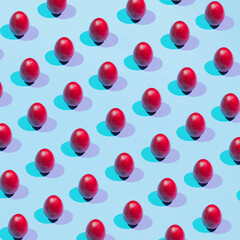 Pattern of colored eggs on a pastel blue background. The concept of minimal food.Easter