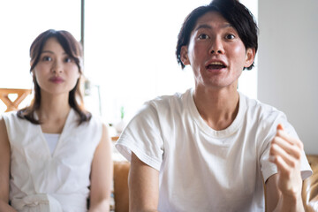 おうちでスポーツ観戦をするカップル