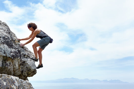 Theres No Mountain Too High. A Woman Scaling A Rockface On A Sunny Day.