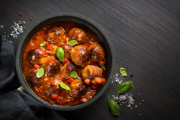 Meatballs in tomato sauce in the skillet on dark stone table. Top view copy space.