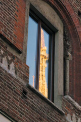 Ancient landmark architecture "Duomo di Milano" under the morning sunlight, reflected in the old brick building windows. ミラノ市街の古いレンガ造りの建物の窓に映り込んだ晴天下、朝日を受け神々しく輝くミラノ大聖堂の塔。