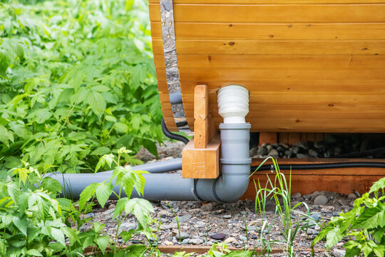 Plastic sewer and water pipes leading to a wooden cottage