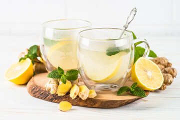 Obraz na płótnie Canvas Ginger tea with lemon and mint in glass mug. Healthy hot vitamin drink.