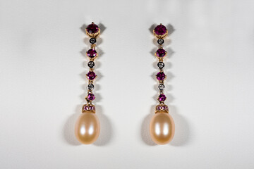Yellow gold earrings with rubies, diamonds and pearls on a white background