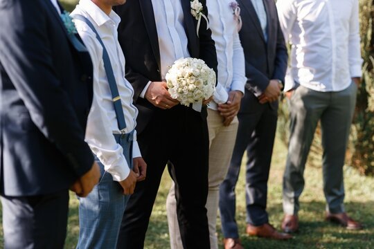 the groom's friends in suits and shirts without faces lined up with the groom and folded their hands in front of them