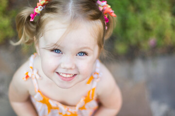 Little girl with blue eyes laughs and looks at the camera