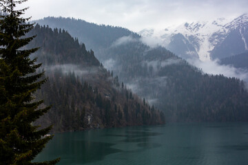 Lake Ritsa in winter in Abkhazia in a haze of fog at dawn