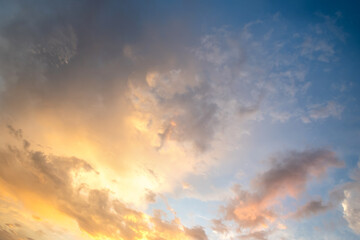 Dramatic sunset landscape picture with puffy clouds lit by orange setting sun and blue sky