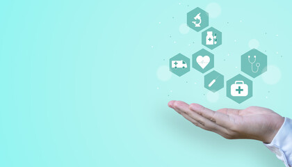 A hand holding a floating icon of healthcare and medical on a turquoise background with copy space.