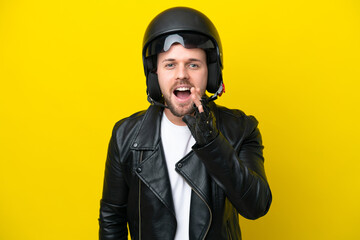 Young caucasian man with a motorcycle helmet isolated on yellow background shouting with mouth wide open