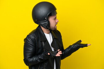 Young caucasian man with a motorcycle helmet isolated on yellow background with surprise expression while looking side