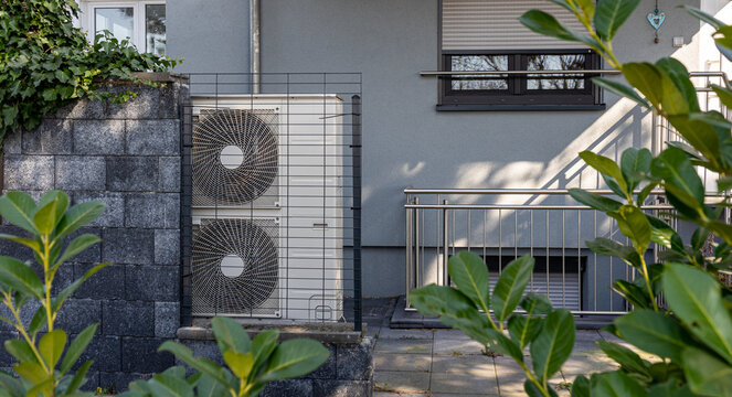 Air source heat pumps installed on the garden front  of a modern house. Renewable energy concept 