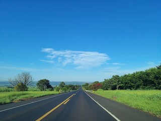Asphalt road with green grass and hills and a beautiful blue Ceu. Sao Paulo, Brazil.