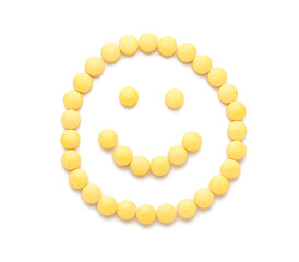 Obraz premium Happy smiley made of yellow pills on white background