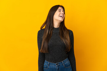 Teenager Brazilian girl isolated on yellow background laughing