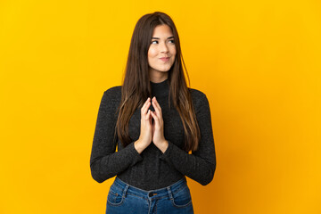 Teenager Brazilian girl isolated on yellow background scheming something