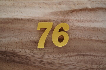 Golden Arabic numerals on a real brown and white wooden floor number 76
