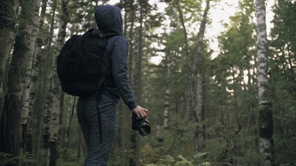 Fototapeta na wymiar Traveler photographing scenic view in forest. One caucasian woman shooting nice magic look. Girl take photo video on dslr mirrorless camera. Professional photographer travel with backpack. Outdoor.