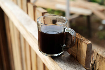 A cup of black coffee on a wooden fence