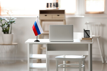 Comfortable workplace with Russian flag and modern laptop in light room