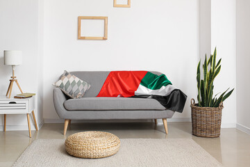 Grey sofa with UAE flag in interior of light living room
