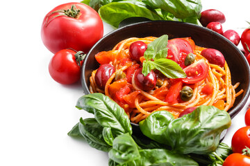 Frying pan with delicious Pasta Puttanesca and ingredients on white background, closeup