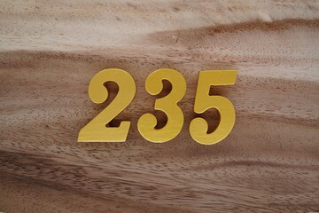 Golden Arabic numerals on a real brown and white wooden floor number 235