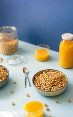 Breakfast concept with cold cereals and orange juice on blue background