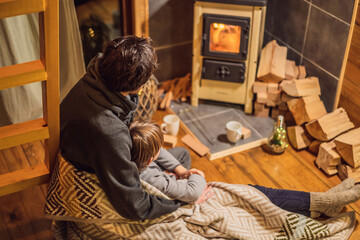 Fototapeta na wymiar Dad and son spend time by the fireplace in Glamping. Rest in the mountains in Glamping. Cozy fireplace in a mountain house