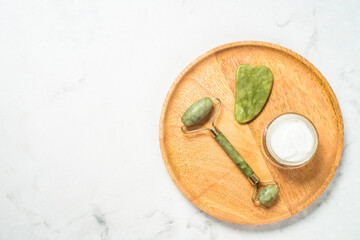 Scincare product, spa product. Jade roller and gua sha massagers with face cream. Anti aging therapy. Top view with on white background.
