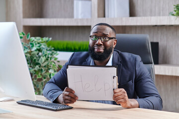 Young Unhappy Businessman Sitting And Holding White Flag With The Text Help In Office