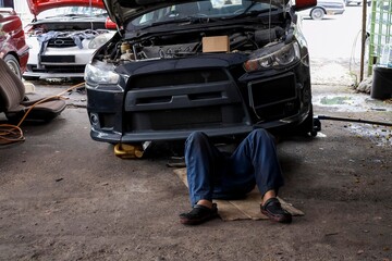A mechanic lying under a car to change engine oil